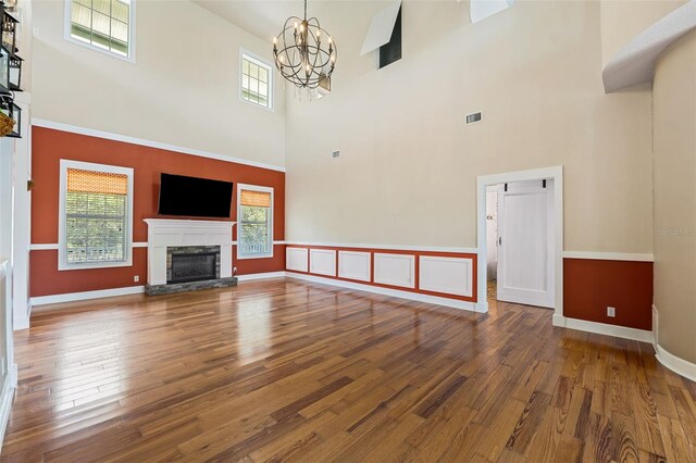 unfurnished living room featuring a notable chandelier, hardwood / wood-style floors, and a high ceiling