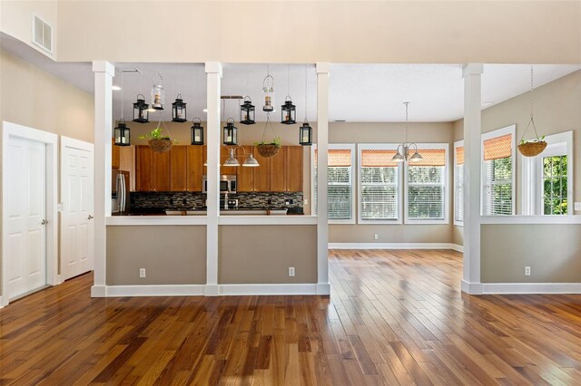 kitchen with appliances with stainless steel finishes, plenty of natural light, hardwood / wood-style flooring, and tasteful backsplash