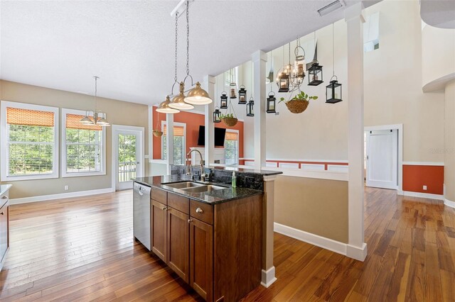 kitchen with dishwasher, hardwood / wood-style floors, sink, an island with sink, and a notable chandelier