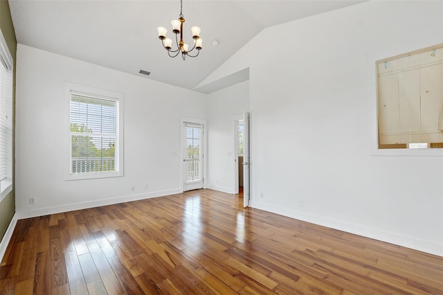 unfurnished room featuring vaulted ceiling, hardwood / wood-style flooring, and a chandelier