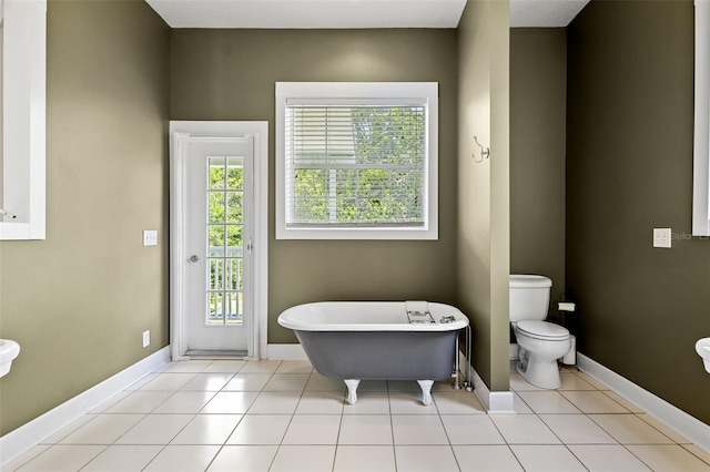 bathroom with a bathing tub, toilet, tile patterned flooring, and a healthy amount of sunlight