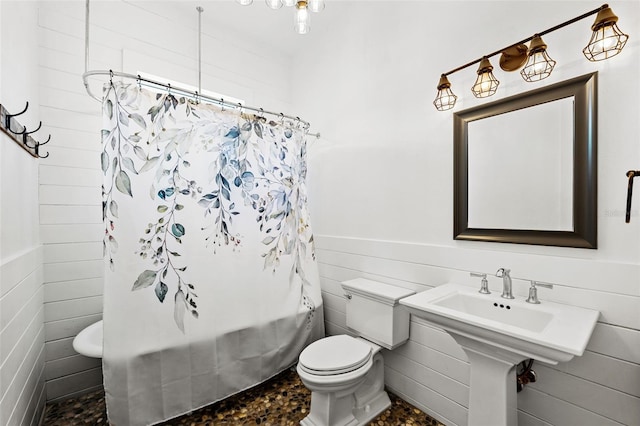 bathroom featuring toilet, shower / bathtub combination with curtain, and tile walls