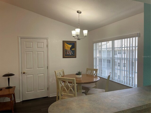 dining space with an inviting chandelier, lofted ceiling, and dark hardwood / wood-style flooring