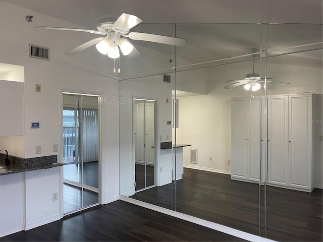 interior space featuring ceiling fan, dark hardwood / wood-style floors, vaulted ceiling, and two closets