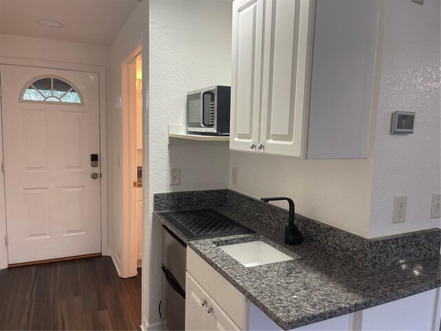 kitchen with white cabinetry, sink, dark stone counters, kitchen peninsula, and dark wood-type flooring