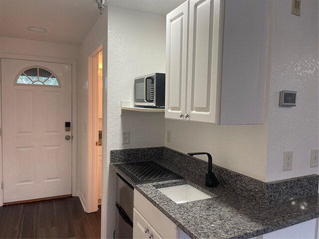 kitchen with white cabinetry, dark hardwood / wood-style floors, sink, and dark stone countertops