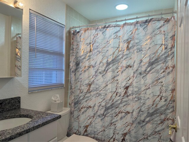 bathroom featuring vanity, curtained shower, and toilet