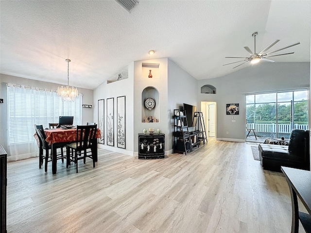 dining space featuring light wood-type flooring, a textured ceiling, high vaulted ceiling, and ceiling fan with notable chandelier