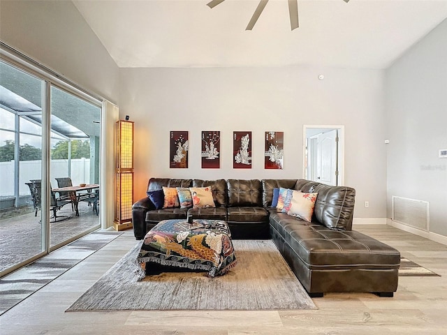 living area with visible vents, high vaulted ceiling, a ceiling fan, light wood finished floors, and baseboards