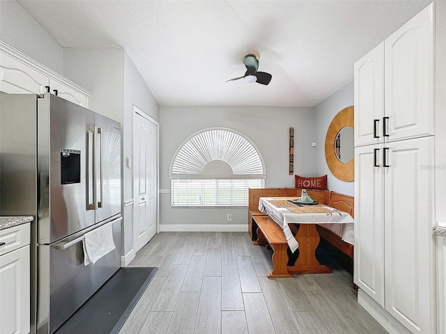 dining area with a textured ceiling, baseboards, light wood-type flooring, and a ceiling fan