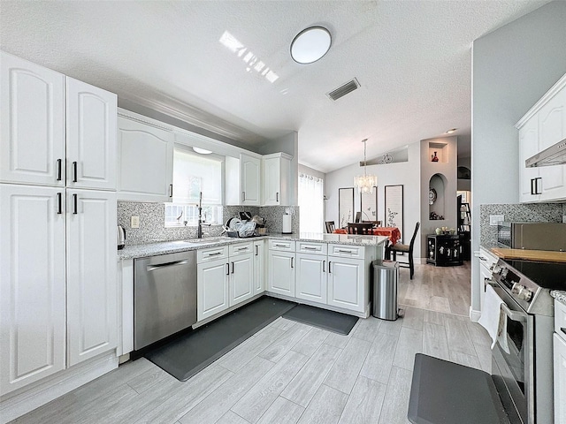 kitchen featuring a peninsula, lofted ceiling, stainless steel appliances, decorative backsplash, and a chandelier