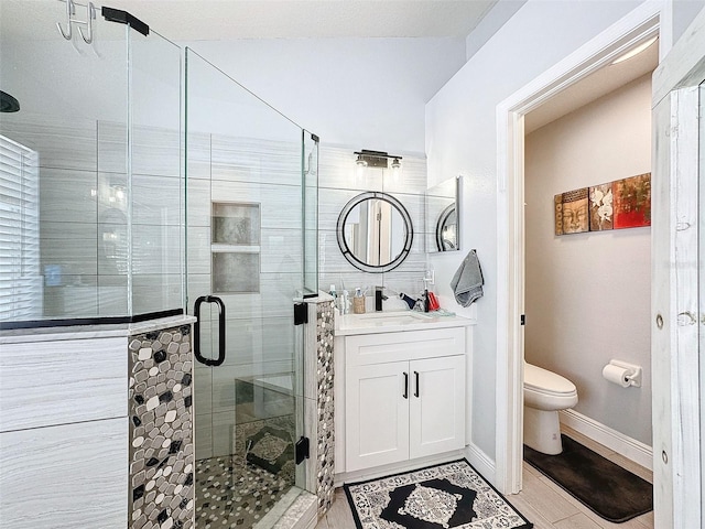 full bathroom featuring vanity, a shower stall, toilet, and baseboards