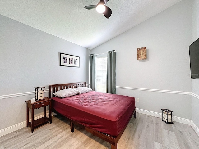 bedroom featuring vaulted ceiling, wood finished floors, baseboards, and a textured ceiling