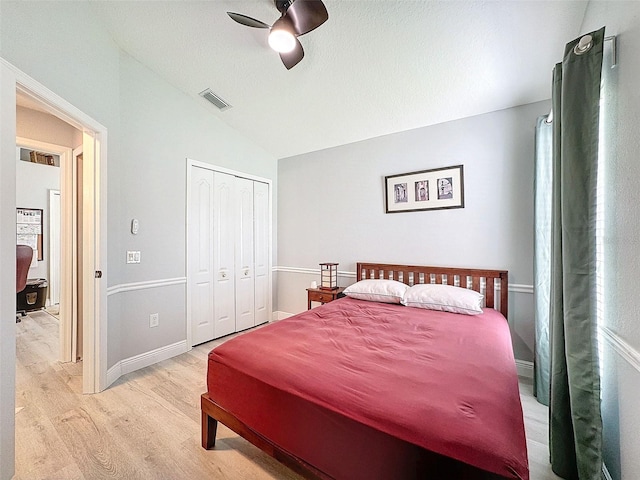 bedroom with a ceiling fan, visible vents, light wood-style flooring, vaulted ceiling, and a closet