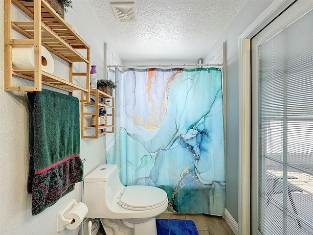 bathroom featuring toilet, a textured ceiling, and curtained shower