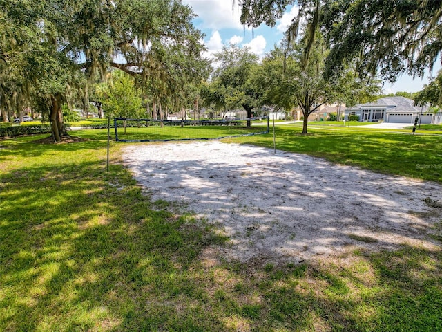 view of property's community featuring a garage, a lawn, and volleyball court