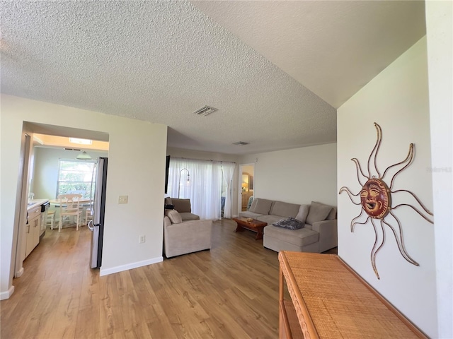 living room with a textured ceiling and light hardwood / wood-style floors