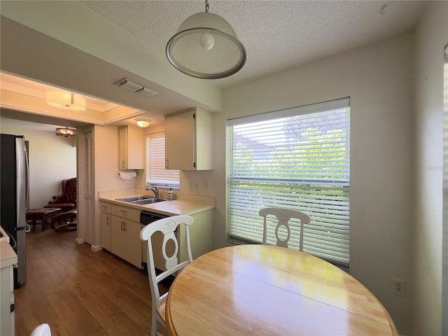 kitchen featuring sink, dishwashing machine, wood-type flooring, a textured ceiling, and stainless steel fridge