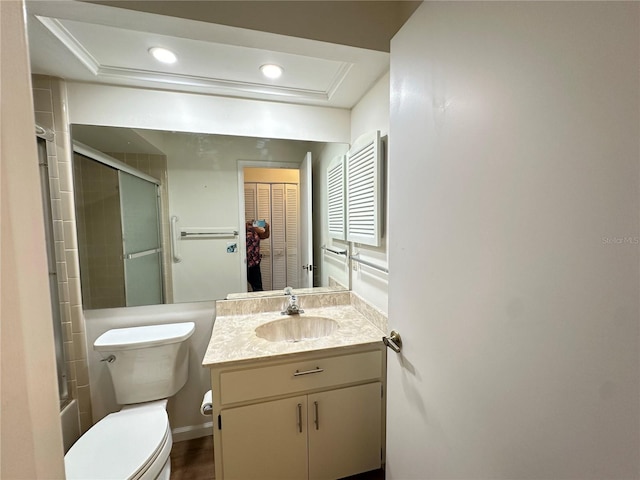 full bathroom featuring a tray ceiling, toilet, vanity, and enclosed tub / shower combo