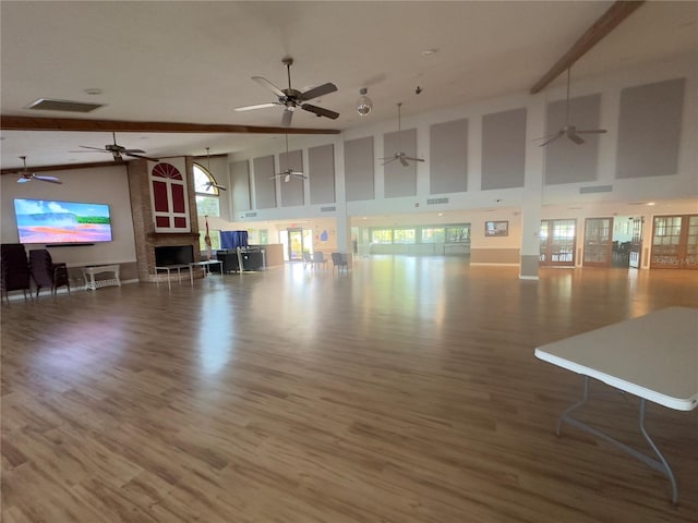 unfurnished living room featuring high vaulted ceiling, ceiling fan, wood-type flooring, and beam ceiling