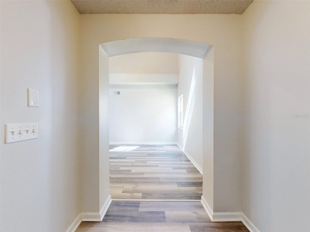 hall with wood-type flooring and a textured ceiling