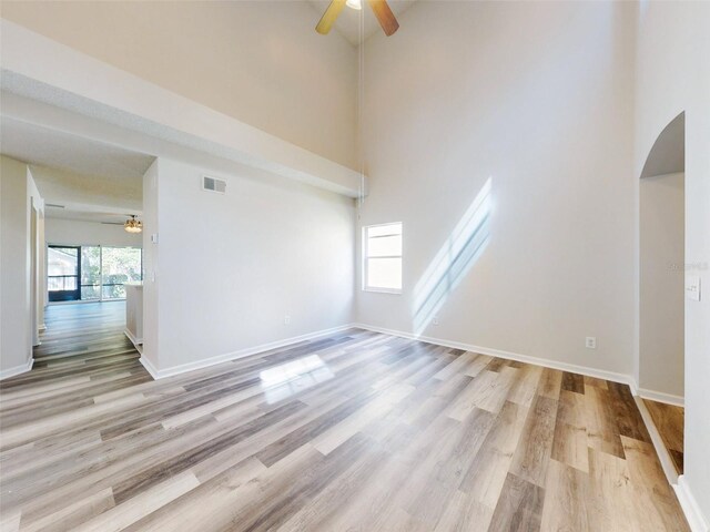 interior space with a high ceiling, ceiling fan, and light hardwood / wood-style flooring