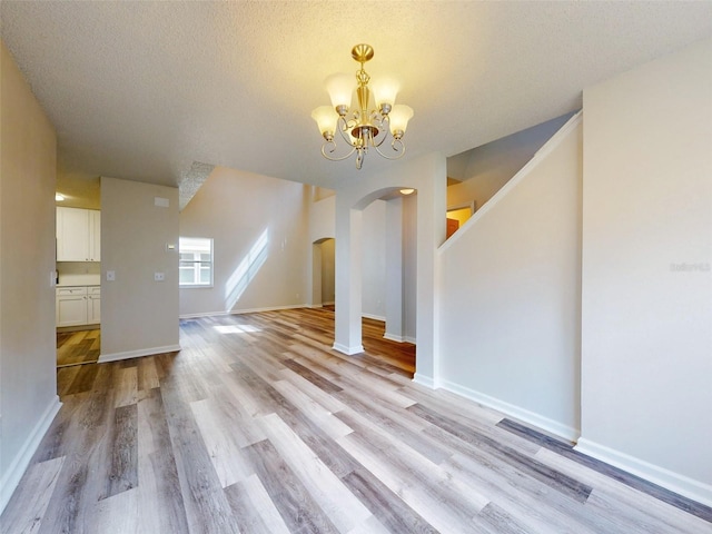 bonus room with a textured ceiling, a notable chandelier, and light hardwood / wood-style flooring