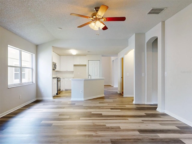 interior space featuring a textured ceiling, light hardwood / wood-style flooring, vaulted ceiling, and ceiling fan