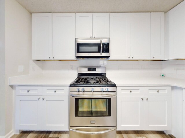 kitchen featuring white cabinets, appliances with stainless steel finishes, decorative backsplash, and light hardwood / wood-style flooring