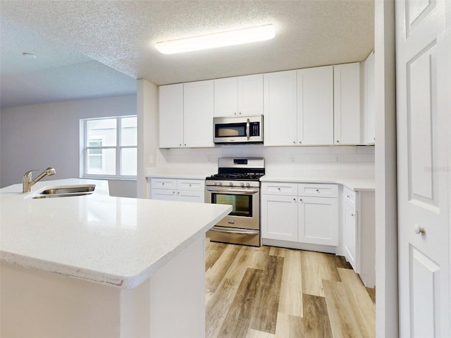 kitchen with light wood-type flooring, white cabinetry, a textured ceiling, stainless steel appliances, and sink