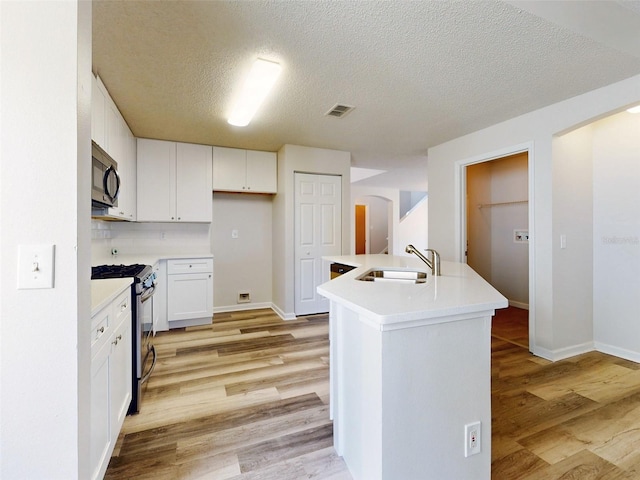 kitchen featuring white cabinets, gas stove, sink, and light hardwood / wood-style floors