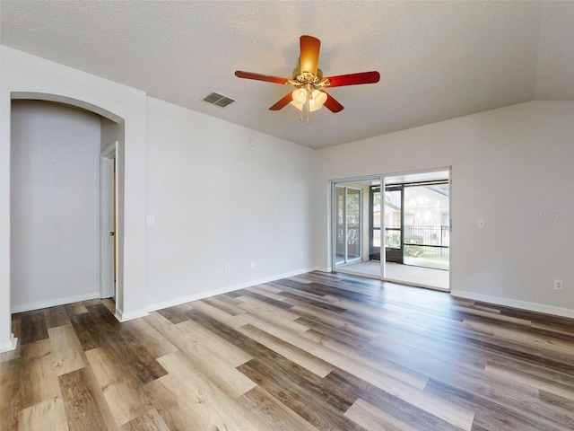 spare room featuring wood-type flooring, vaulted ceiling, a textured ceiling, and ceiling fan