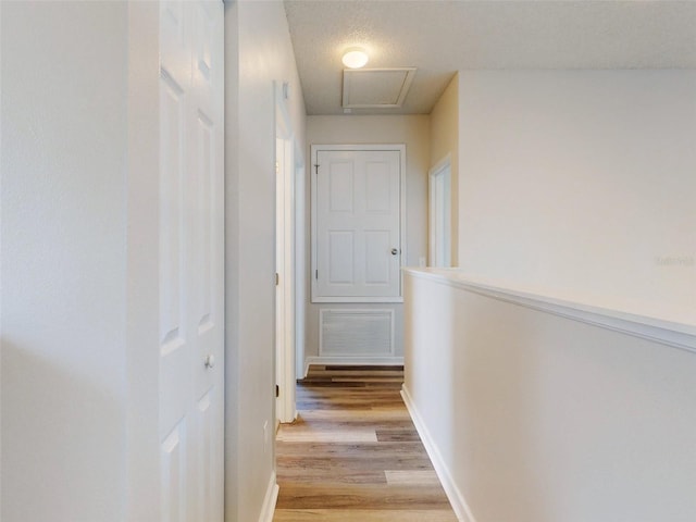 corridor featuring a textured ceiling and light hardwood / wood-style flooring