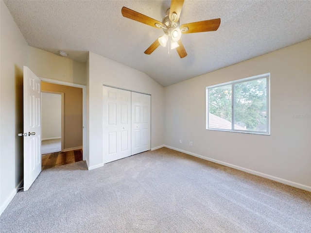 unfurnished bedroom featuring lofted ceiling, a closet, ceiling fan, and carpet floors