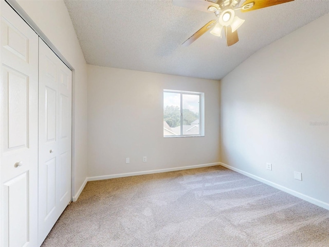 unfurnished bedroom featuring a closet, ceiling fan, light carpet, and a textured ceiling