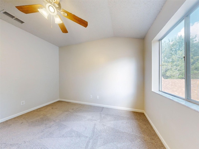 carpeted spare room featuring vaulted ceiling, a textured ceiling, plenty of natural light, and ceiling fan