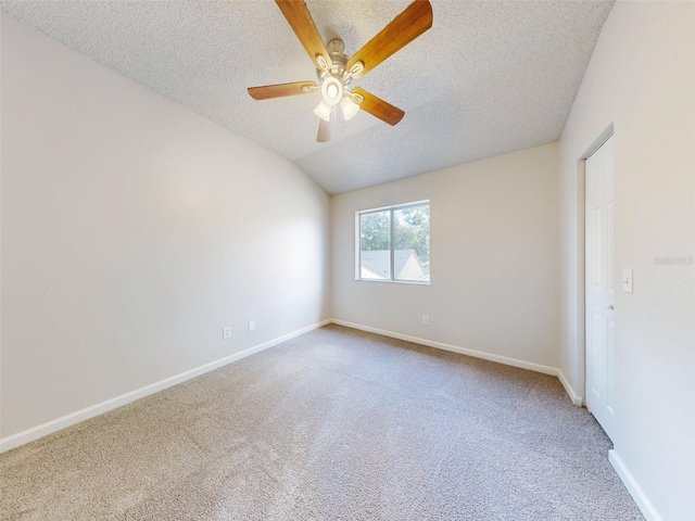 carpeted empty room featuring a textured ceiling, ceiling fan, and vaulted ceiling