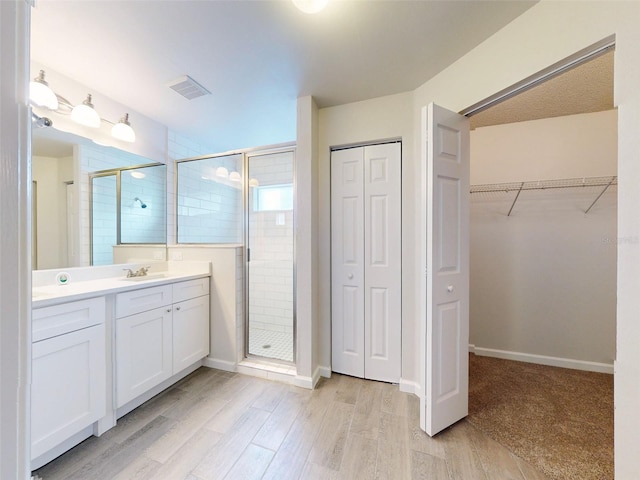 bathroom with a shower with shower door, hardwood / wood-style flooring, and vanity