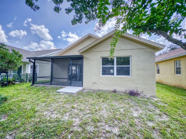 back of property with a lawn and a sunroom