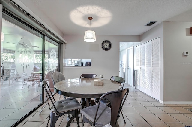 dining space with a textured ceiling and light tile patterned flooring