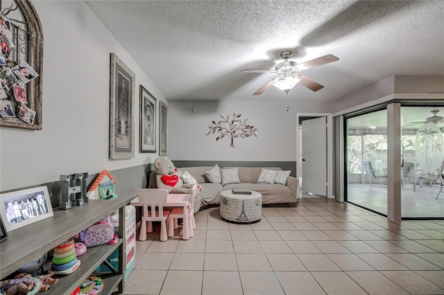 living room with ceiling fan, light tile patterned flooring, and a textured ceiling