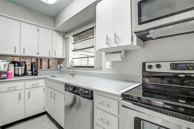 kitchen featuring appliances with stainless steel finishes, white cabinetry, light tile patterned flooring, and sink