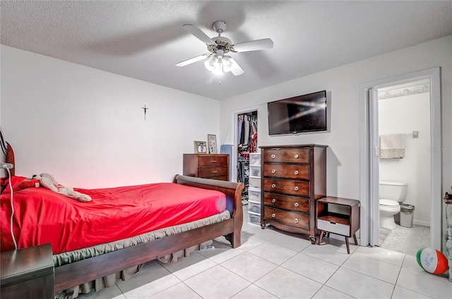 bedroom with a textured ceiling, a closet, light tile patterned floors, ensuite bath, and ceiling fan