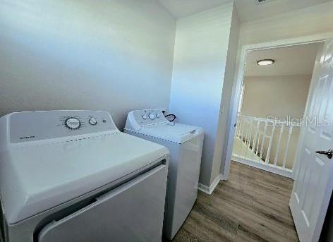 laundry room with washing machine and dryer and hardwood / wood-style floors