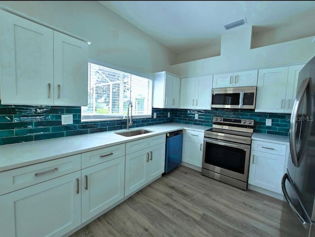 kitchen with light hardwood / wood-style floors, appliances with stainless steel finishes, decorative backsplash, and white cabinets