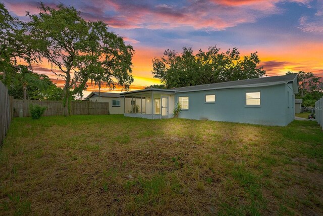 back house at dusk featuring a yard