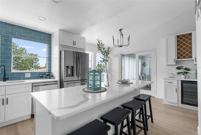 kitchen featuring sink, a center island, wine cooler, a healthy amount of sunlight, and stainless steel fridge with ice dispenser