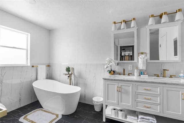 bathroom featuring a freestanding bath, double vanity, a sink, and marble finish floor