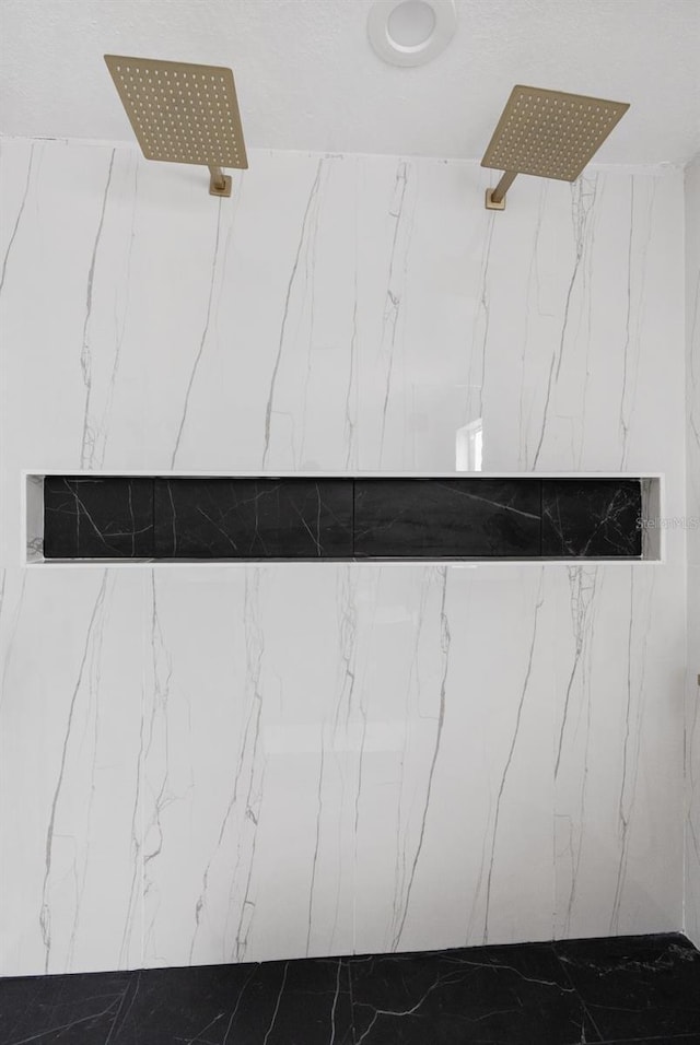 interior details featuring a marble finish shower