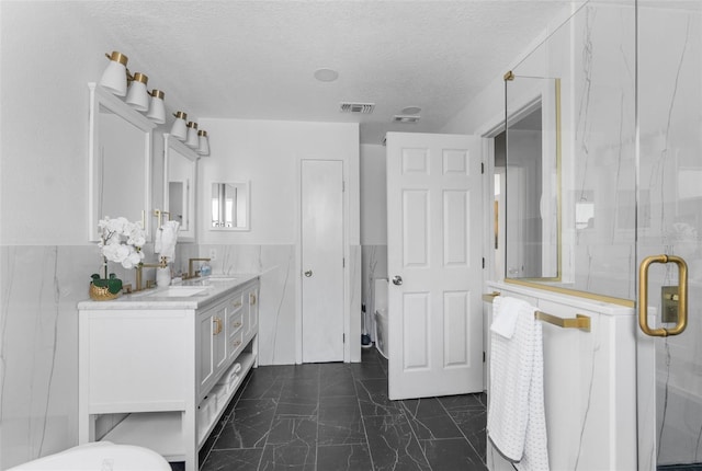 bathroom with tile patterned flooring, tile walls, a textured ceiling, and vanity